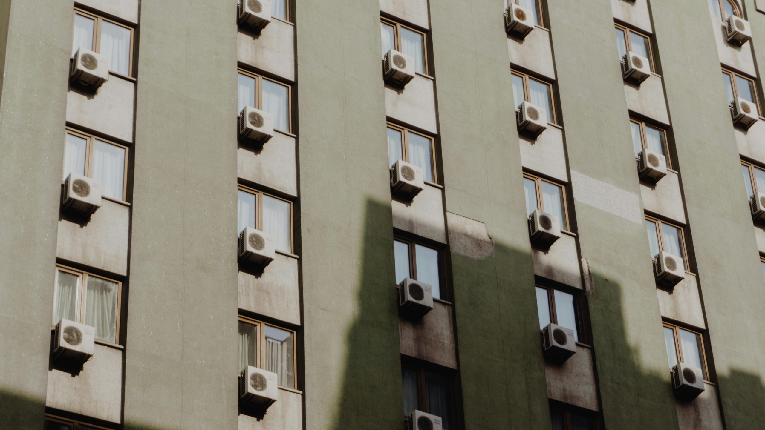Facade of a city apartment building equipped with air conditioners on each window.